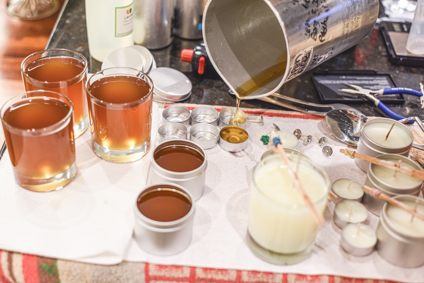 Creative occupation of candle making showing the pouring of liquid wax into jars